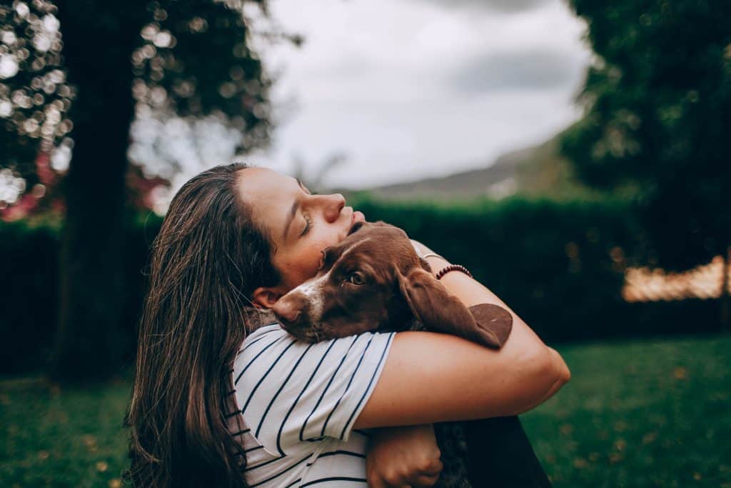 woman hugging black dog